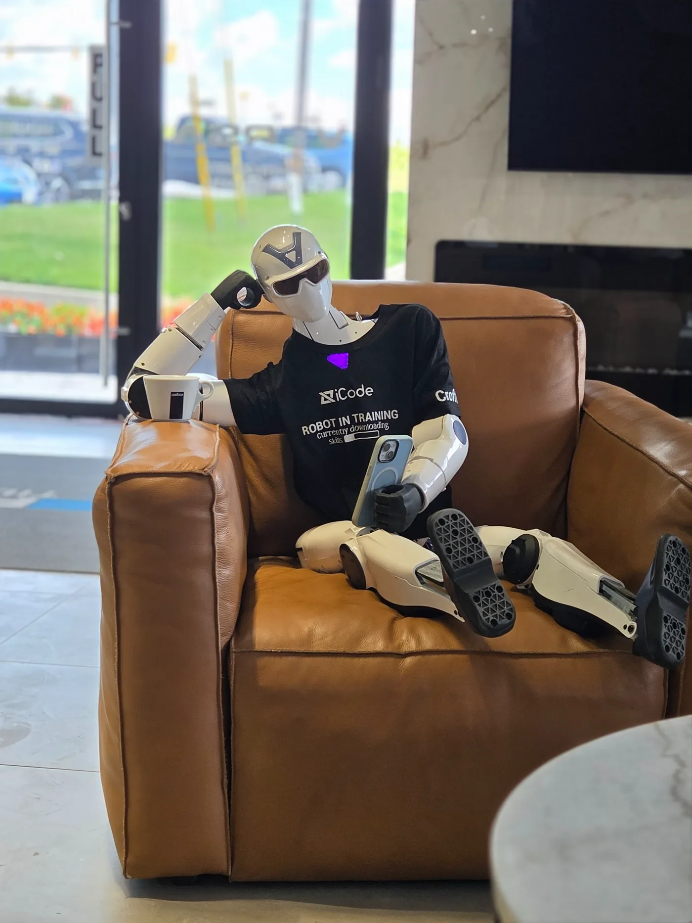 iZak relaxing in a leather chair with a cup of coffee and a phone